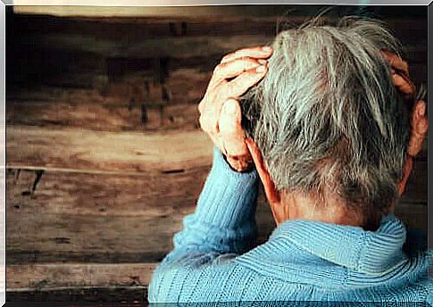 An elderly person with his head in his hands.