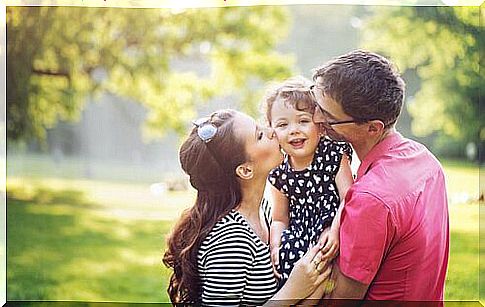 Parents kissing their daughter